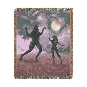Woven blanket in purple hues design featuring a person and wolf dancing under the moon.